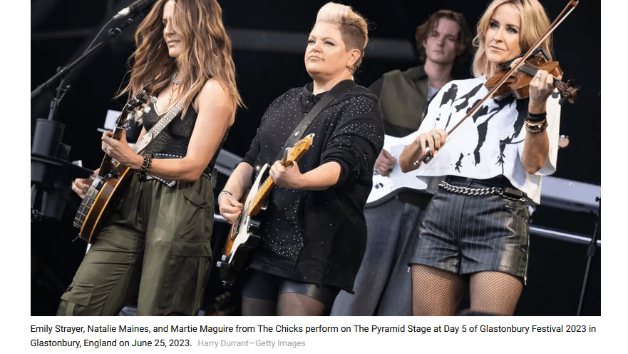Three women on stage perform with musical instruments