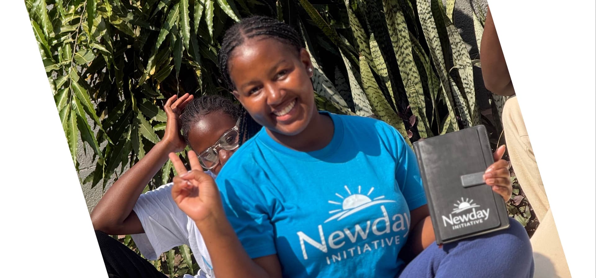 Founder of Newday Initiative wearing a blue initiative T-shirt and holding a Newday Initiative notebook on the initiative’s official launch day.
