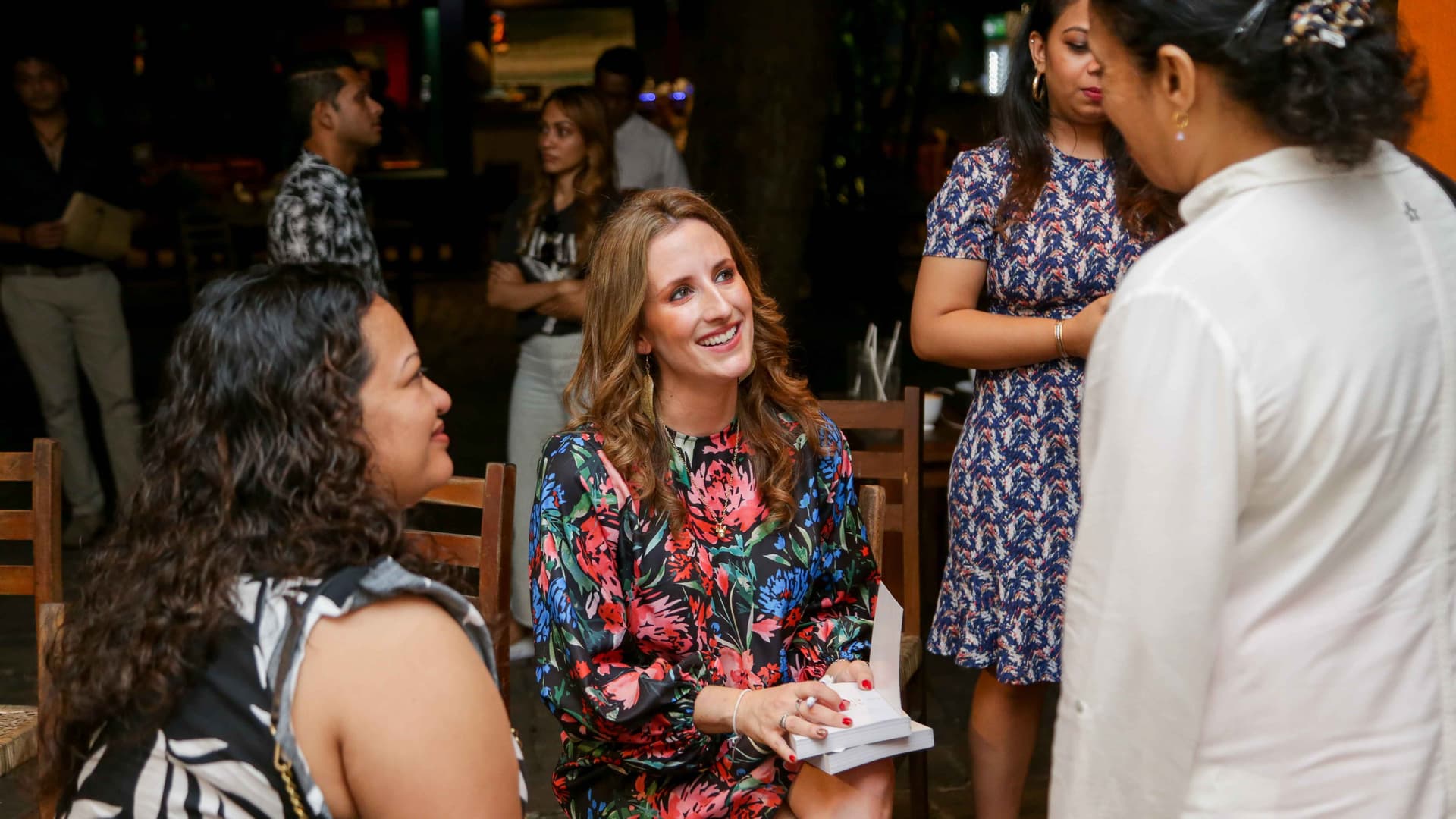 Three people connect and converse openly at an event. They are smiling and engaged.