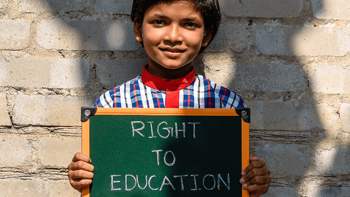 A little girl holding a small board in which it is written a Right To Education