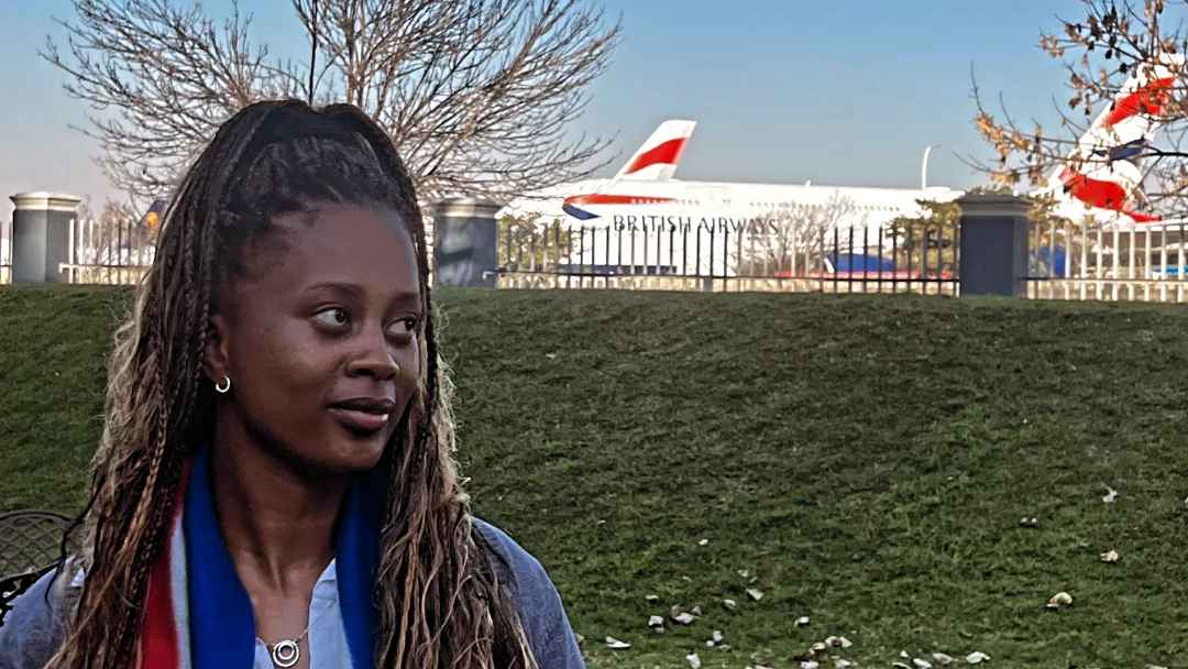 A young Black woman stands in front of an airplane, her expression calm and full of quiet determination. The plane behind her symbolizes movement, transition, and a future taking flight.
