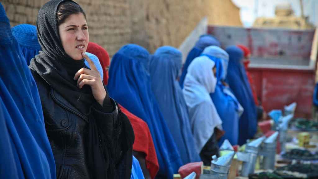 An Afghan girl looking confused or worried among Afghan women wearing blue burqas.