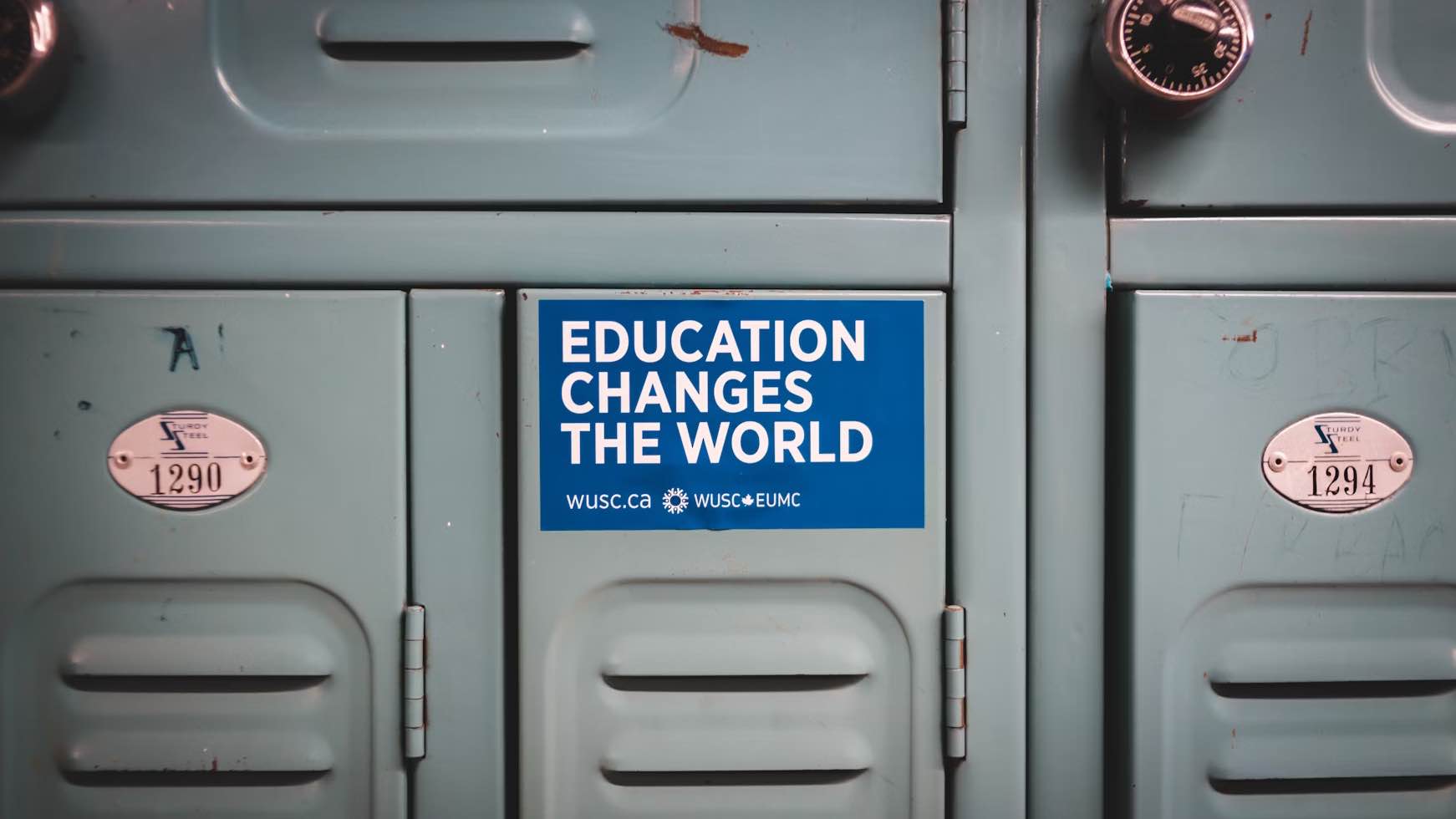 Picture of blue sticker saying “Education changes the world” (in white) glued on a school grey locker