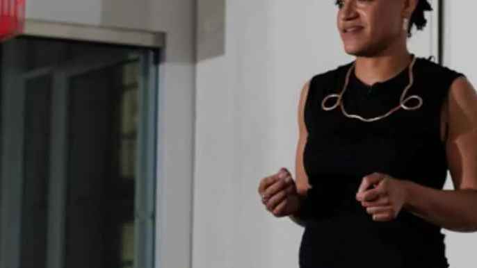 Image of a woman speaking with a her necklace prominent.