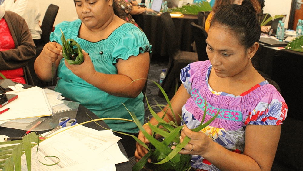 Two women weaving coconut fronds at the Learning Day